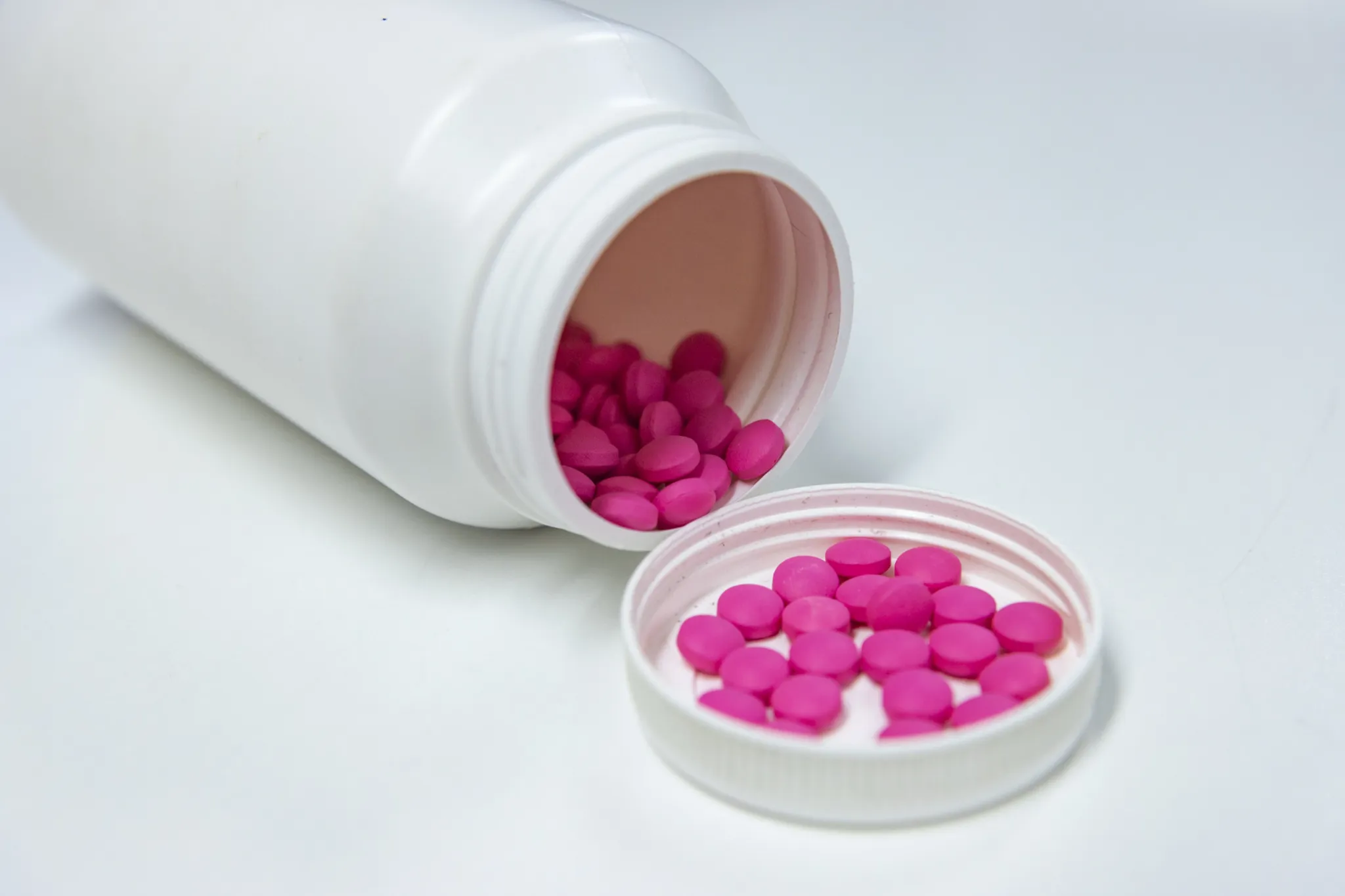 Pink tablets beside an open medicine bottle